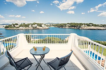 A balcony overlooking a body of water with two drinks on the table