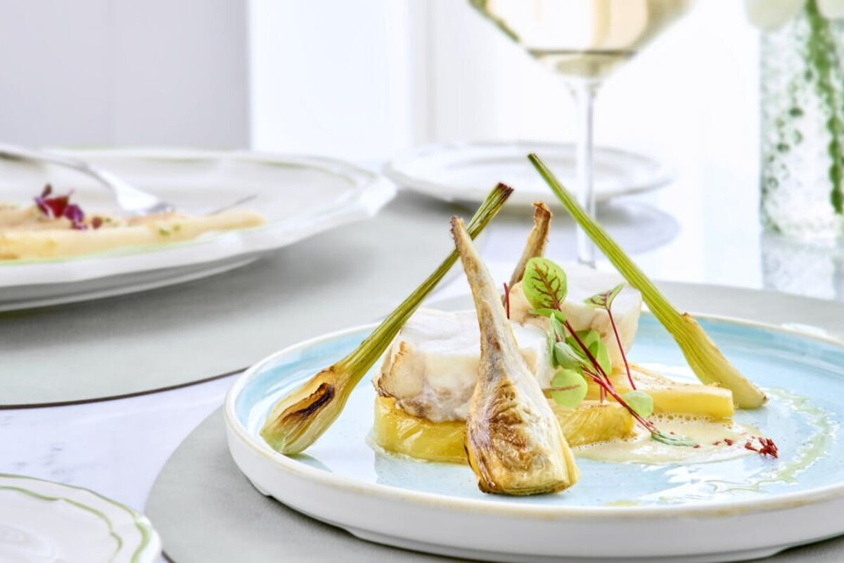 A plate of food on a table with a glass of wine in the background