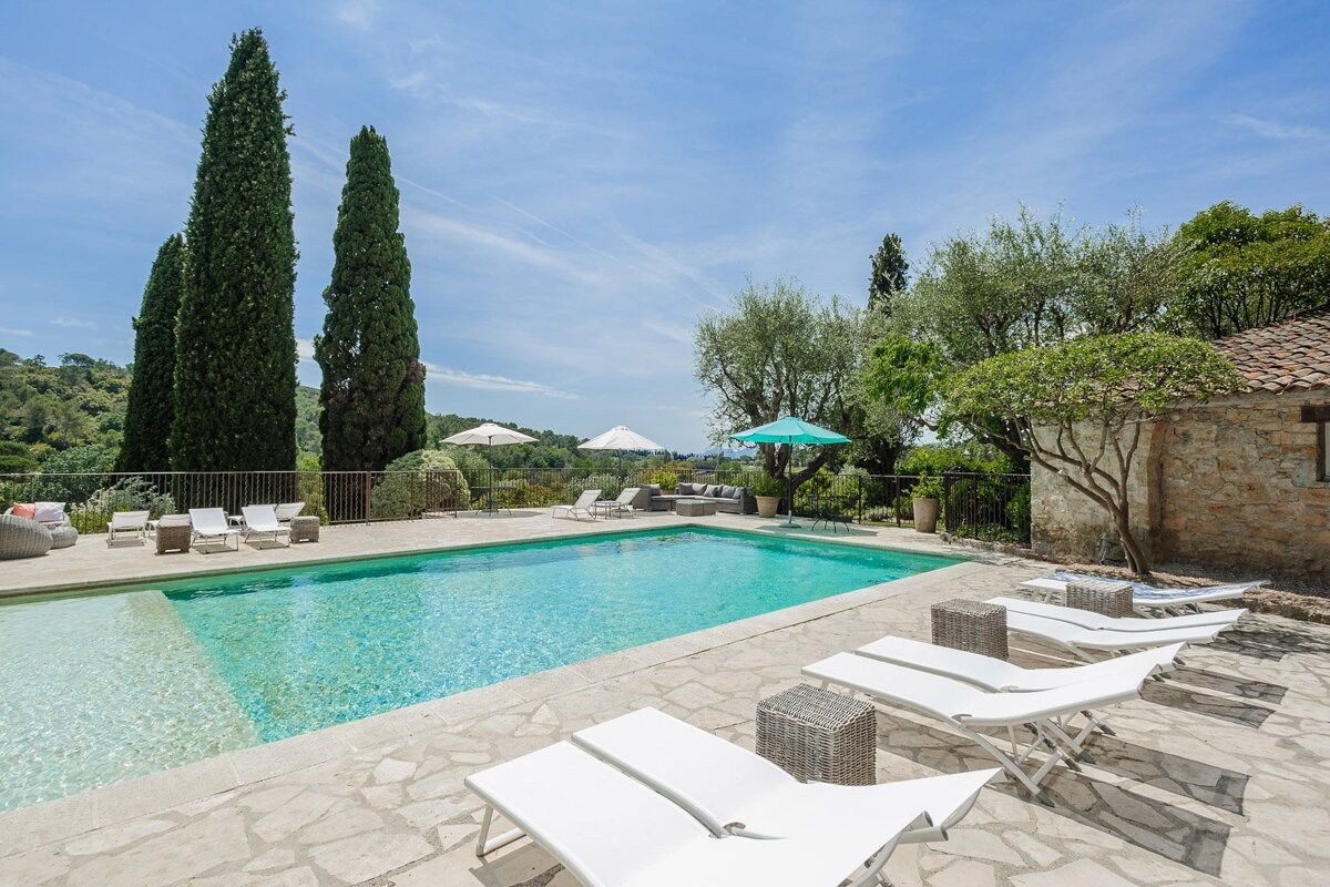 A large swimming pool surrounded by white chairs and umbrellas