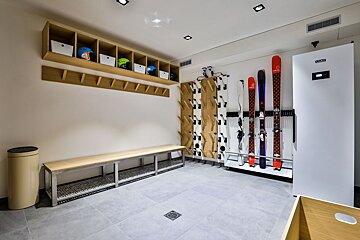 A locker room with skis and helmets hanging on the wall