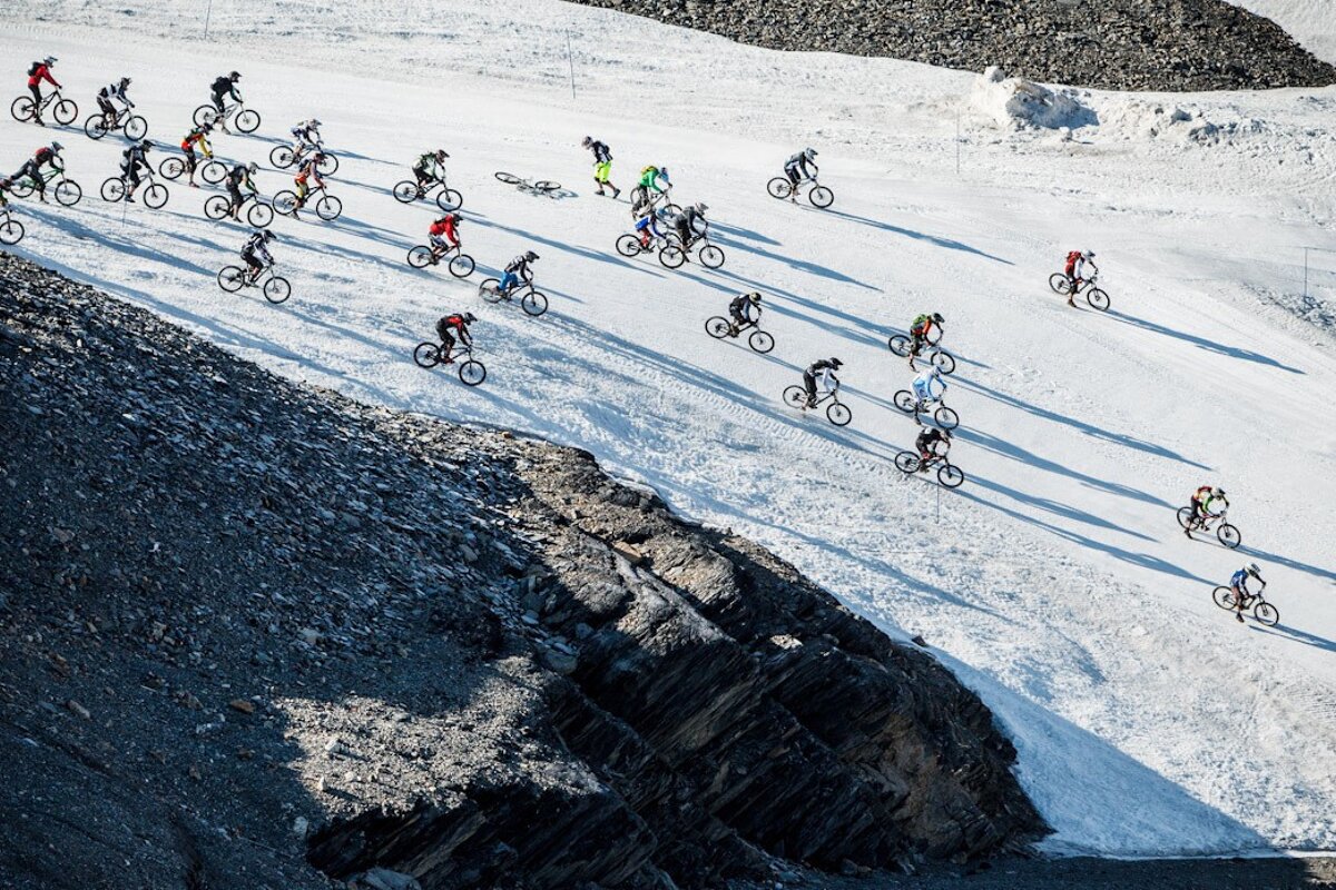 A group of cyclists are riding down a snowy hill