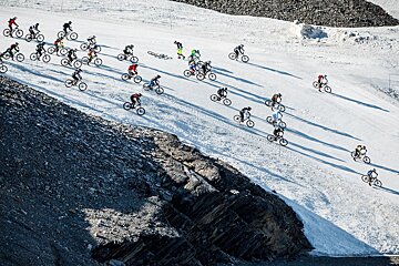 A group of cyclists are riding down a snowy hill