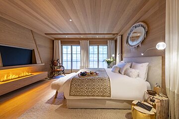 A bedroom with a large bed and a fireplace