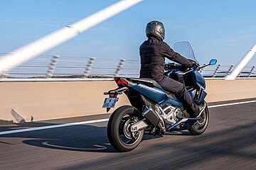 A man is riding a motorcycle on a highway with a license plate that says j-352-jc