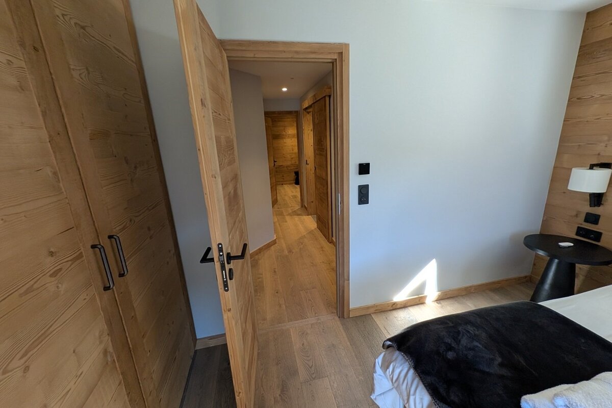 A bedroom with a wooden door leading to a hallway