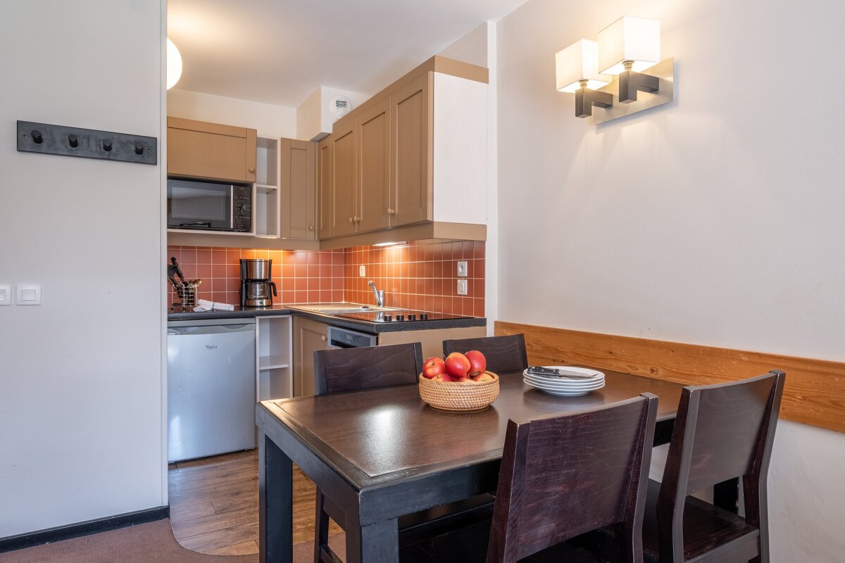 A bowl of apples sits on a table in a kitchen
