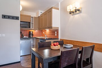 A bowl of apples sits on a table in a kitchen