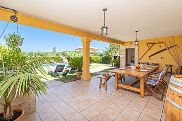 A patio with a table and chairs and a pool in the background