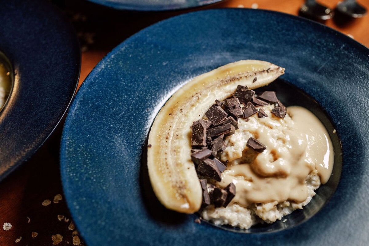 A blue plate of food with a banana and chocolate on top