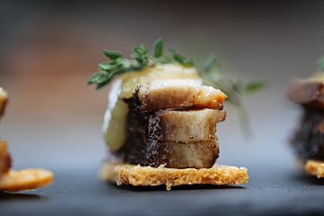 sliced of pork on a small crispbread with herbs on top