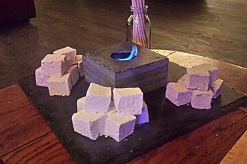 A slate platter of marshmallows with a fire in the middle
