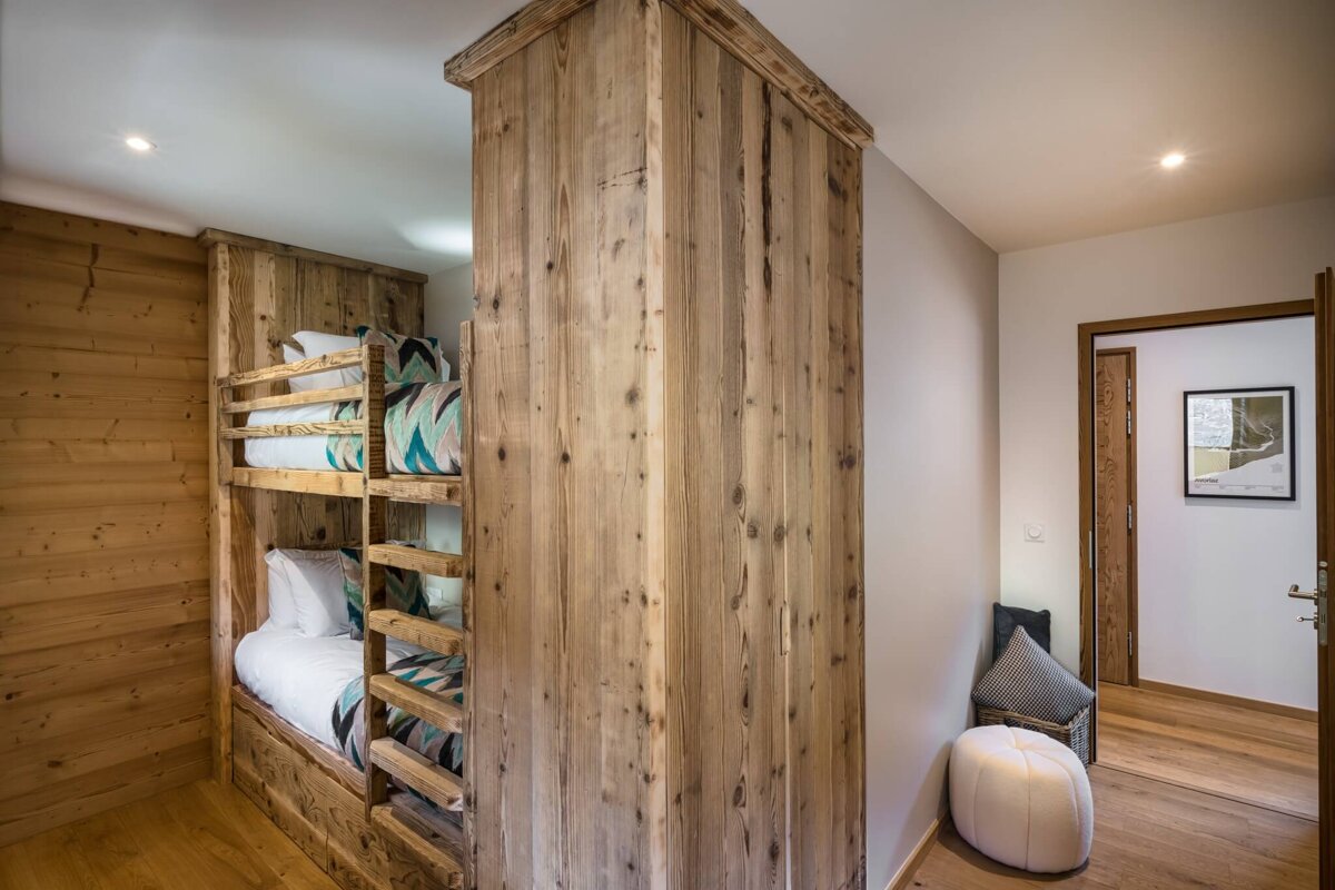 A bunk bed in a wooden room with a picture on the wall