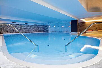 A large indoor swimming pool with stairs leading to it