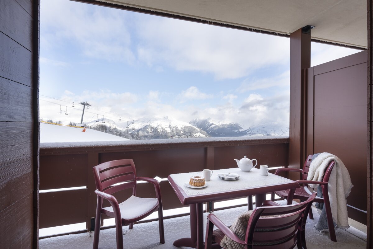 A balcony with a table and chairs and a view of snowy mountains