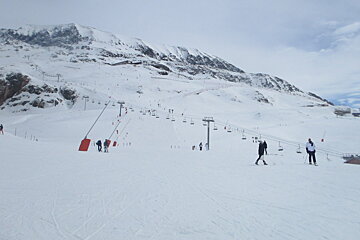a couple of people walking across the piste