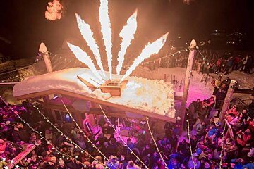 A crowd of people watching a fireworks display in the snow