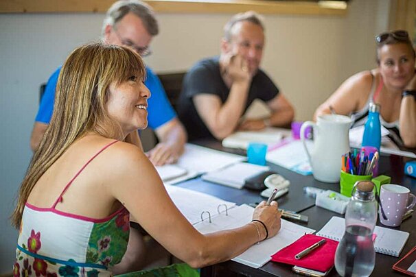 A woman sits at a table with a notebook with the letter u on it