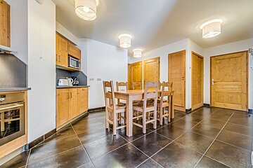 A kitchen with wooden cabinets and a table and chairs