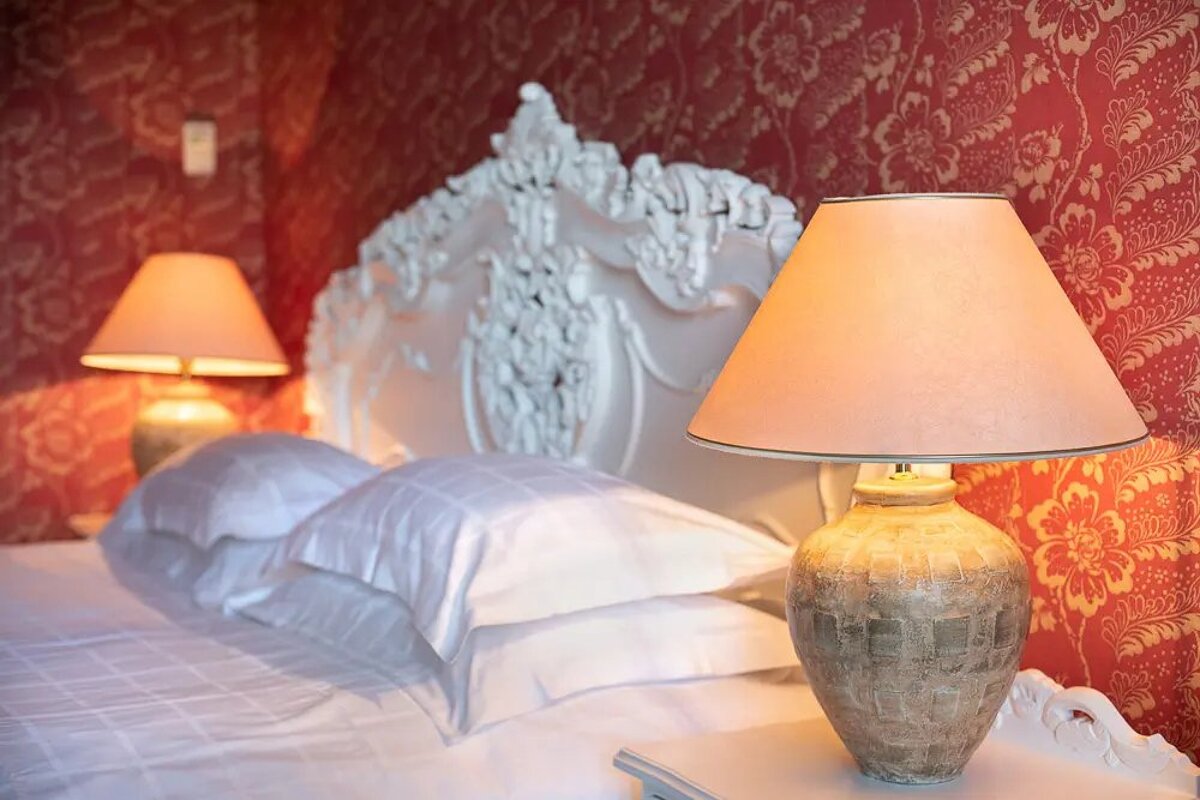 Two lamps sit on a nightstand in front of a bed