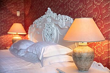 Two lamps sit on a nightstand in front of a bed