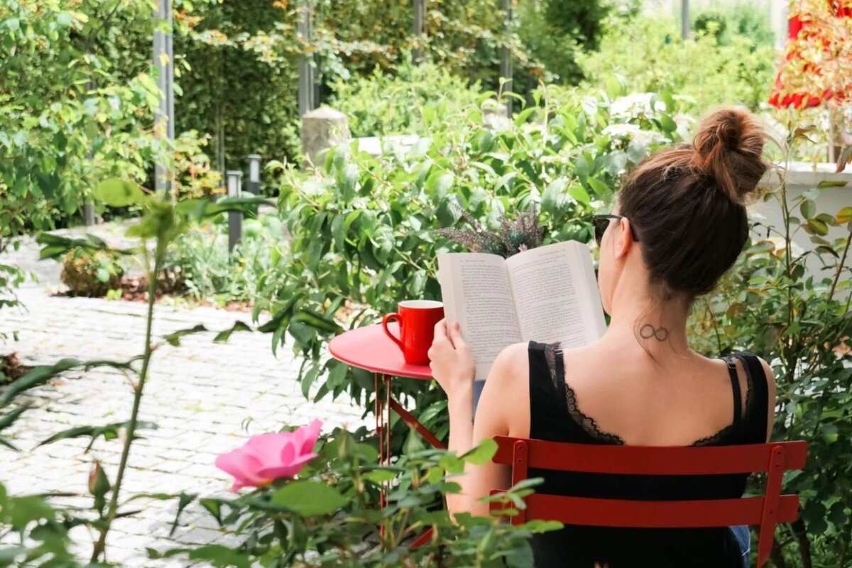 A woman with a tattoo on her neck reading a book