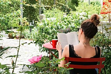 A woman with a tattoo on her neck reading a book