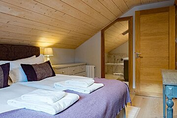 A bedroom with a purple blanket and white towels on the bed