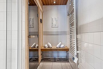 A bathroom with towels on a bench and a towel rack