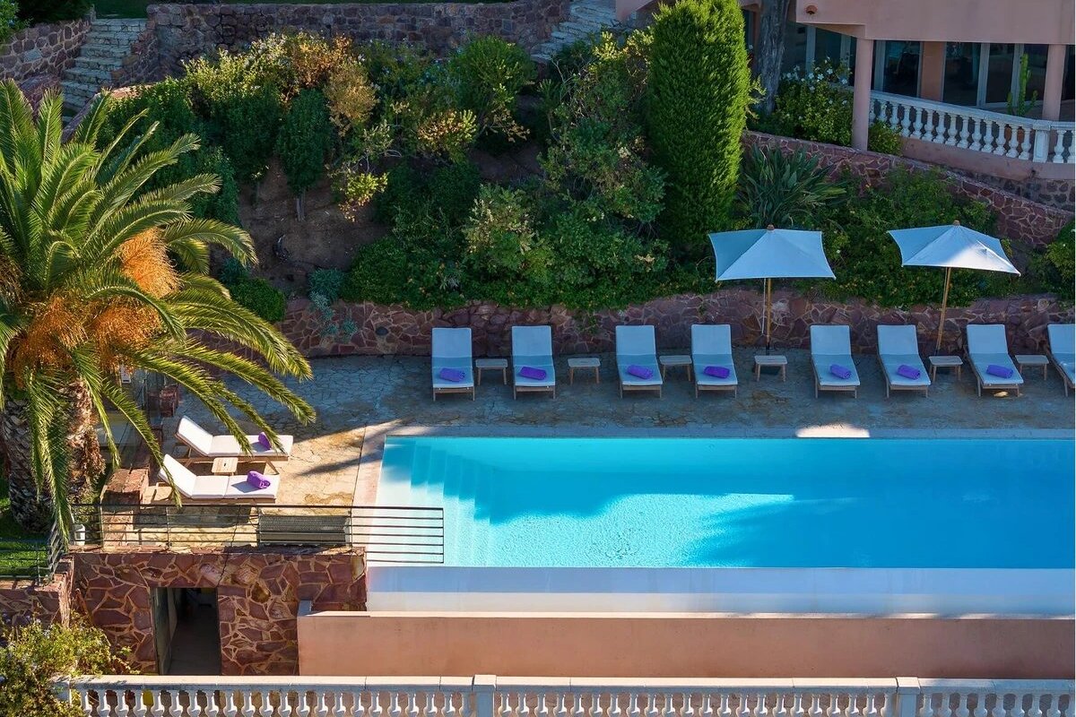 A large swimming pool surrounded by chairs and umbrellas