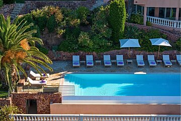 A large swimming pool surrounded by chairs and umbrellas