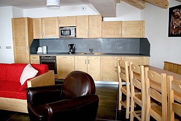 A kitchen with wooden cabinets and a red couch