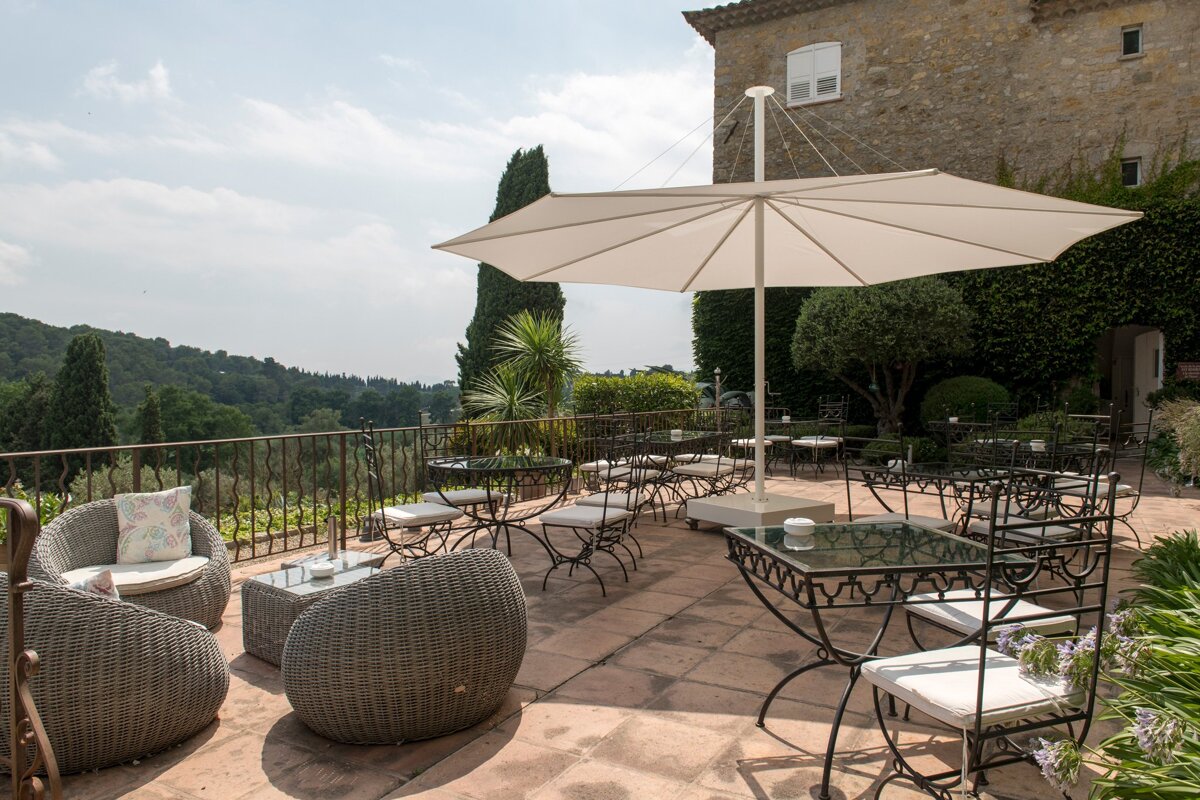 A patio with tables and chairs under an umbrella