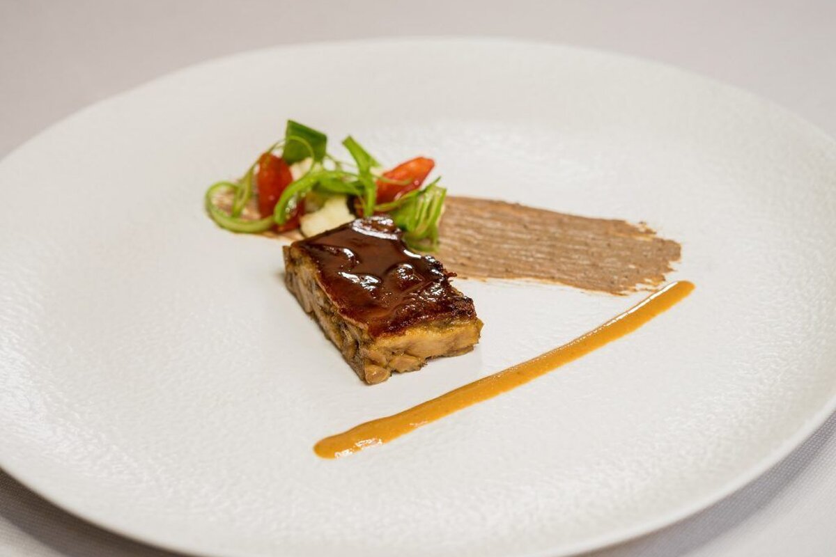 A white plate with a piece of meat and vegetables on it