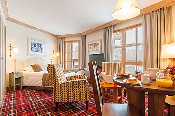 A hotel room with a table and chairs and a bed