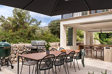 A large green egg grill sits next to a table and chairs