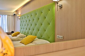 A hotel room with two beds and a green headboard