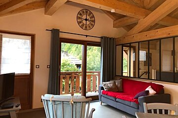 A living room with a red couch and a clock on the wall