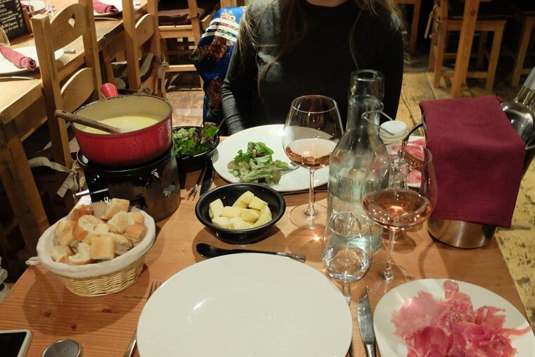 a table with rose wine, fondue and bread