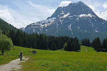 a mountain biker on an open plain with a large mountain behind