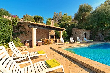 A swimming pool surrounded by chairs and a stone building