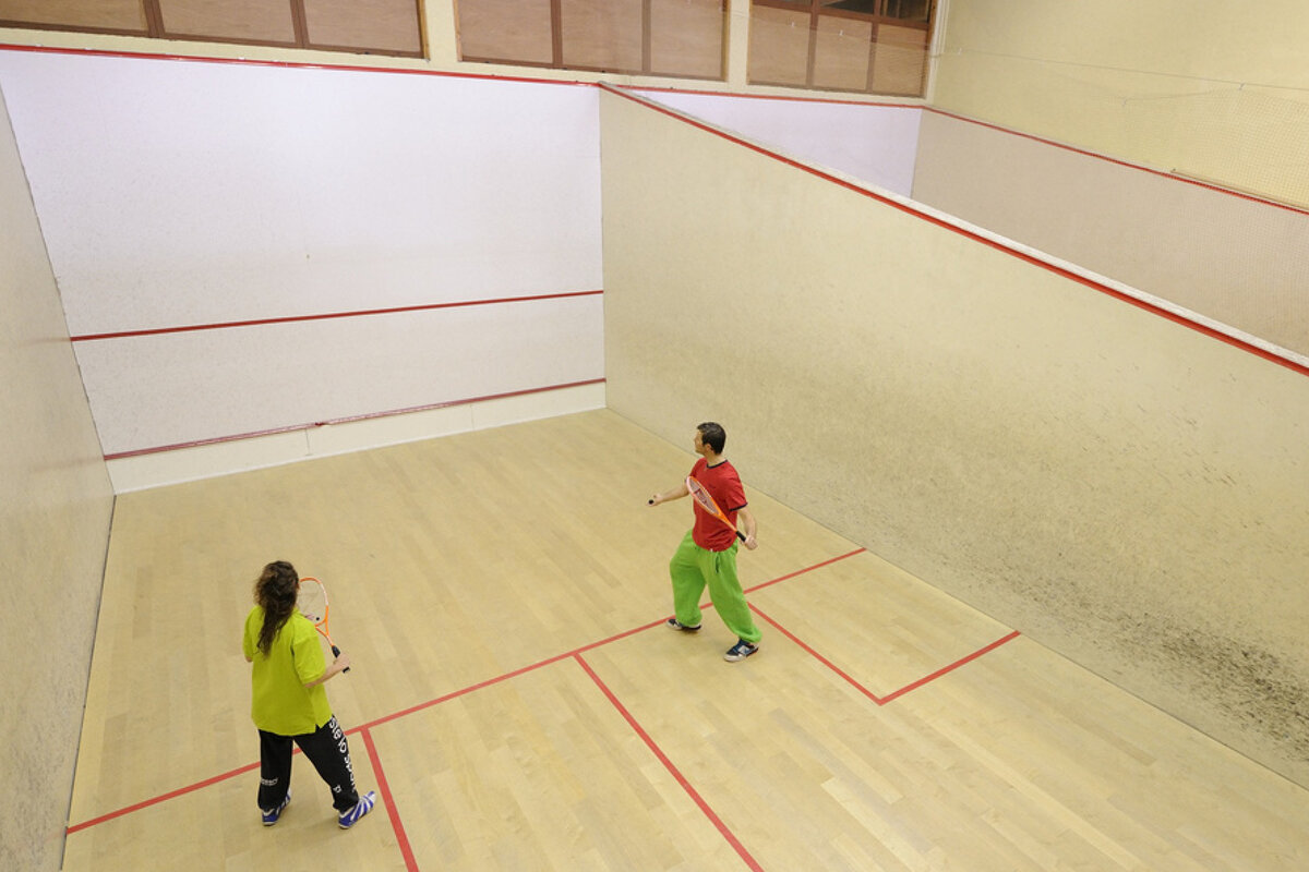 A man and a woman are playing squash on a court