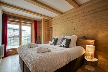 A bedroom with a king size bed and wooden walls