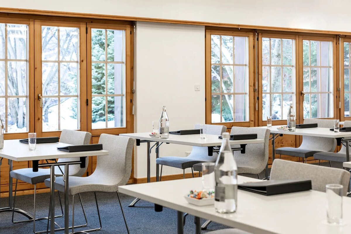 A room with tables and chairs and bottles of water