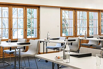 A room with tables and chairs and bottles of water
