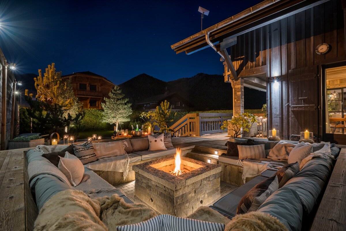 A fire pit sits in the middle of a patio at night