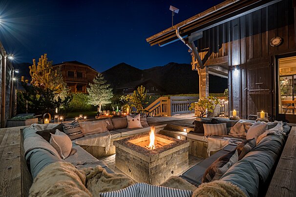 A fire pit sits in the middle of a patio at night
