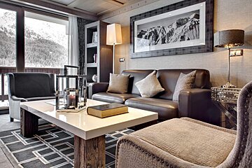 A living room with a couch and chairs and a book on the table
