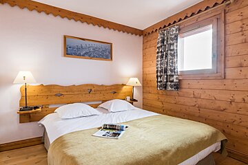 A bedroom with wood paneling and a bed with a magazine on it
