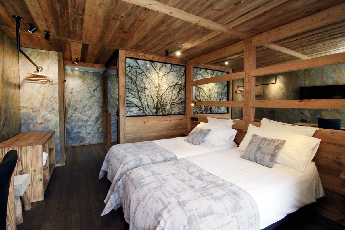 A bedroom with two beds and a picture of trees on the wall