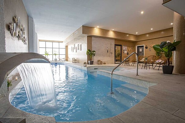 A large indoor swimming pool with a waterfall in the middle